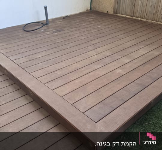 דק עץ חדש בחצר עם דשא סינתטי